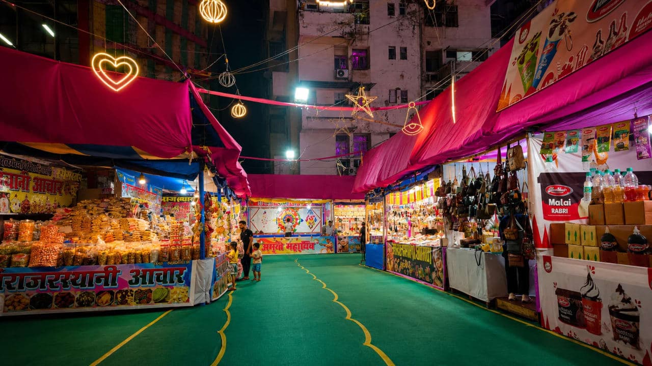 Night view of a seasonal fair in Patna featuring brightly decorated stalls, hanging lights, local food counters, and a lively carnival atmosphere.