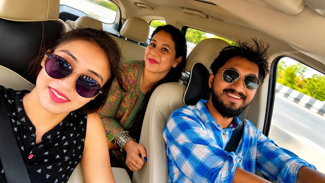 Three friends travelling together in a car on their way to Akshardham Temple in Delhi, smiling for a selfie during a summer trip that brought together a school friendship, family, and a week of unforgettable adventures.