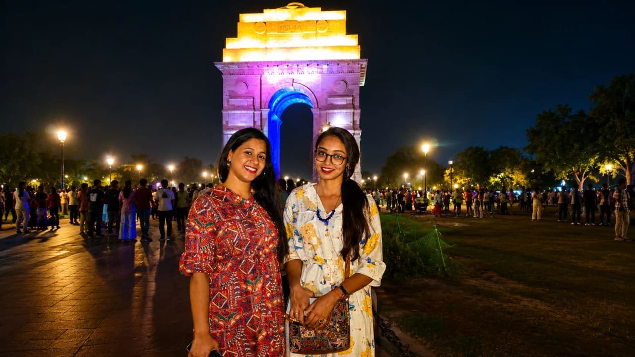 Three friends enjoying an evening at India Gate in New Delhi, posing for a photograph amidst the lively crowd and illuminated monument. The visit was part of a memorable week of sightseeing, friendship, food, and fun before the start of their much-awaited trip.
