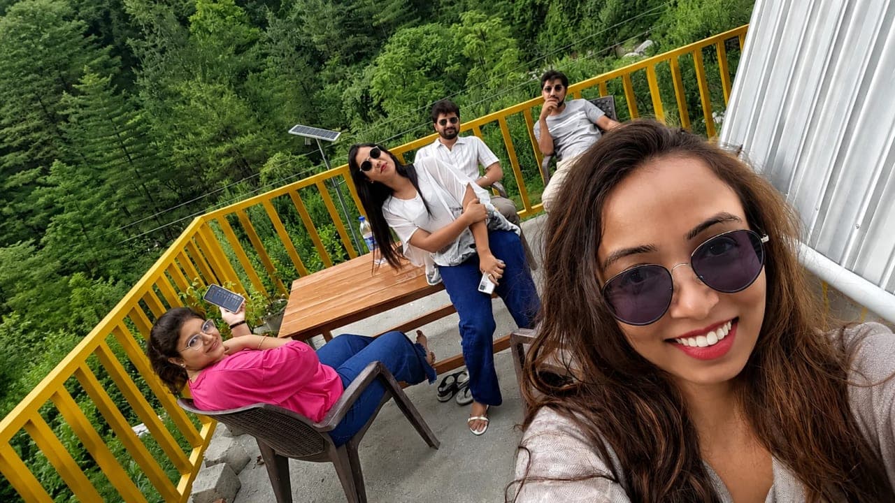 Friends relaxing at a hillside café in Jibhi, enjoying mountain views and a peaceful break during their trip.