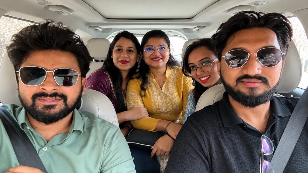 Five friends smiling for a selfie inside a car during their return journey from Jibhi, capturing one of the final moments of a memorable mountain road trip together.