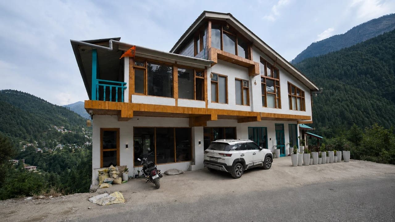 Mountain-view hotel in Jibhi surrounded by pine-covered hills, featuring modern wooden architecture and scenic valley views where the travellers stayed during their Himachal Pradesh road trip.
