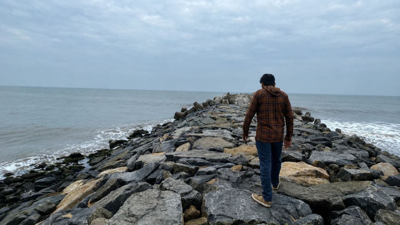 Traveller enjoying a peaceful walk on large coastal rocks beside the ocean in Pondicherry.