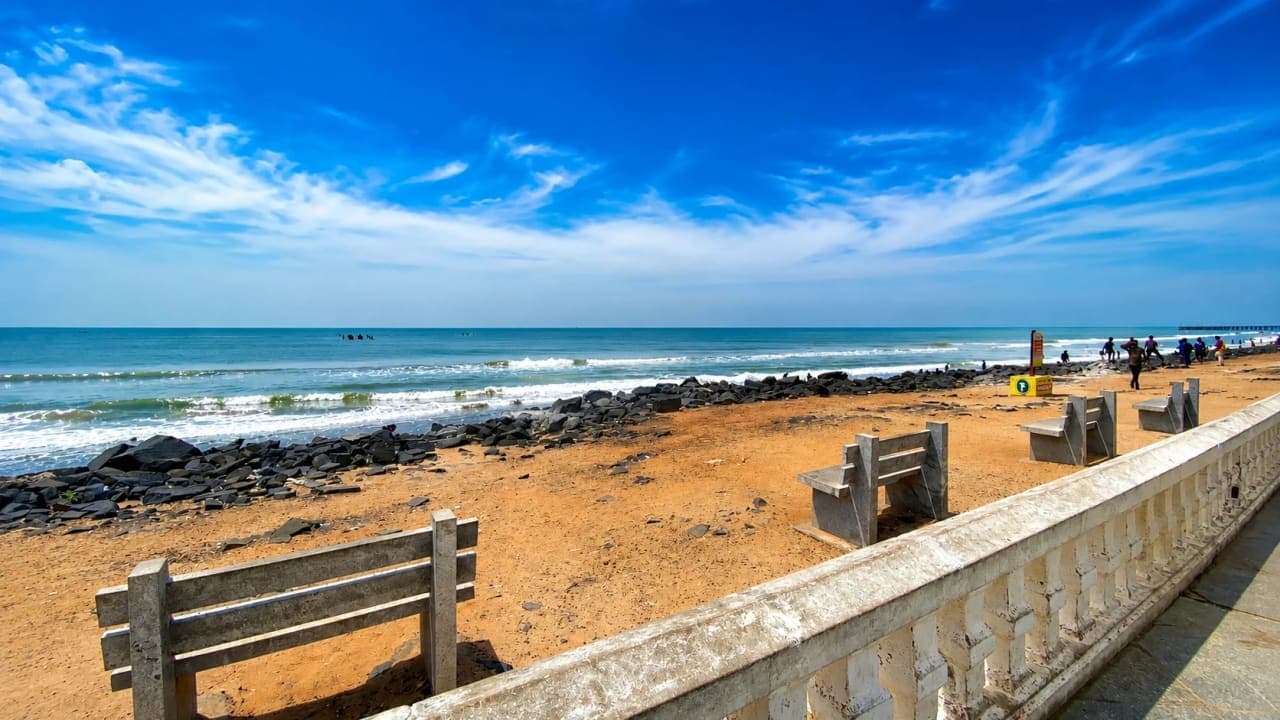 Scenic view of Rock Beach in Puducherry with the Bay of Bengal, rocky shoreline, and a bright blue sky.