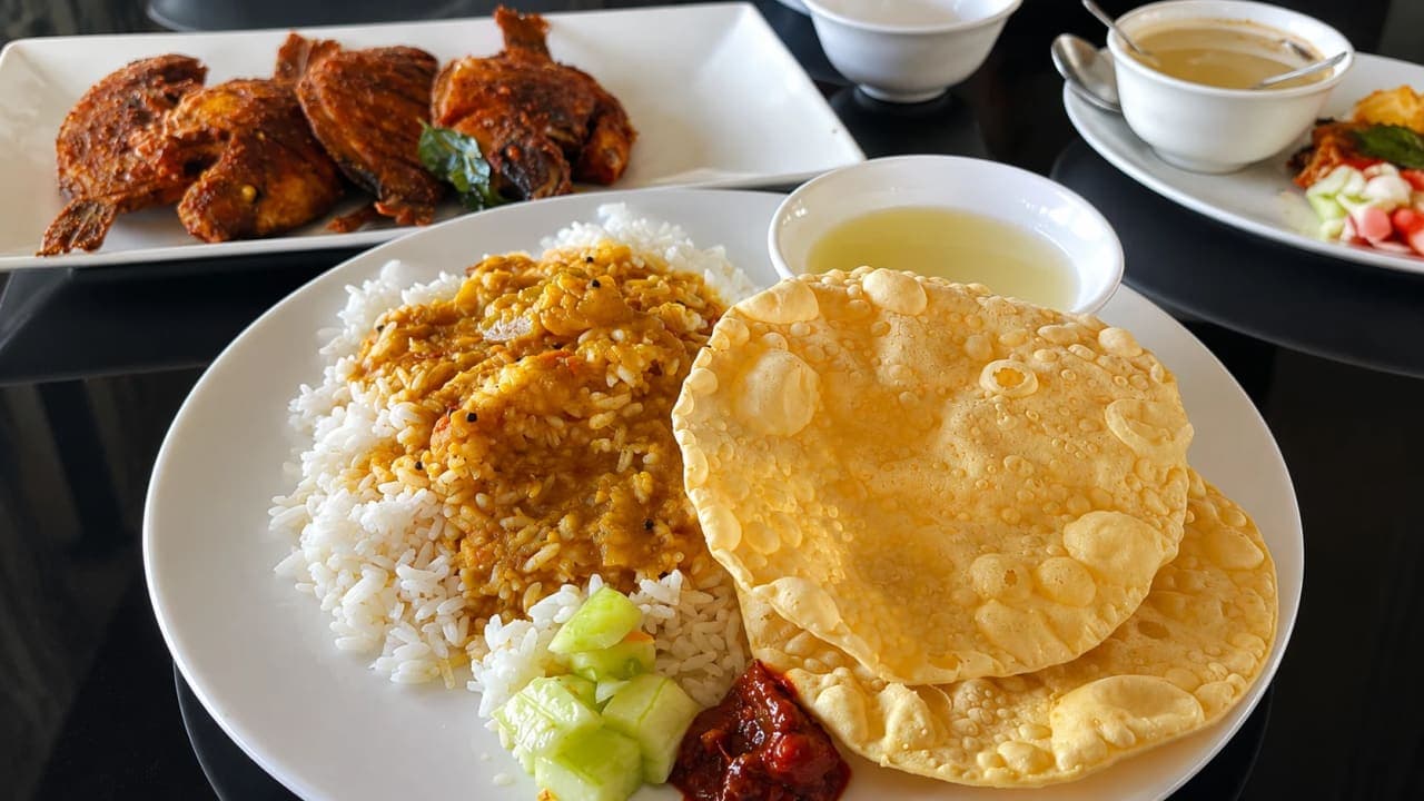 Traditional Kerala houseboat lunch featuring rice, sambar, vegetable curry, fish, salad, papad, and pickle served while cruising through the Alleppey backwaters.