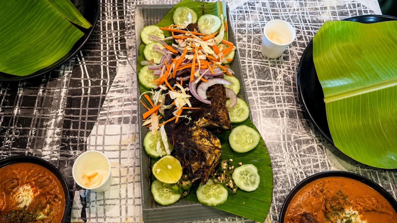 Traditional Kerala meal served at a restaurant in Periyar, featuring Kerala parotta, chicken curry, fish, and payasam after our elephant ride.