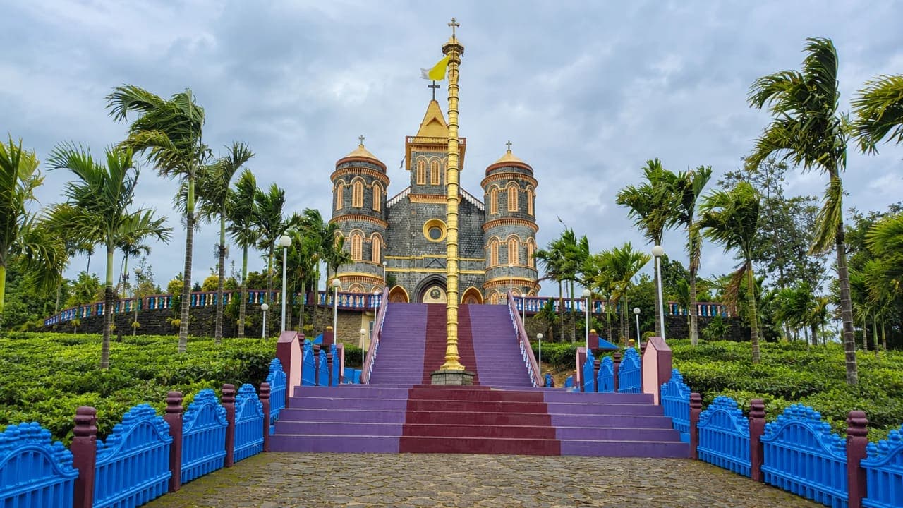 Pattumala Church surrounded by lush tea plantations and mist-covered hills near Thekkady.