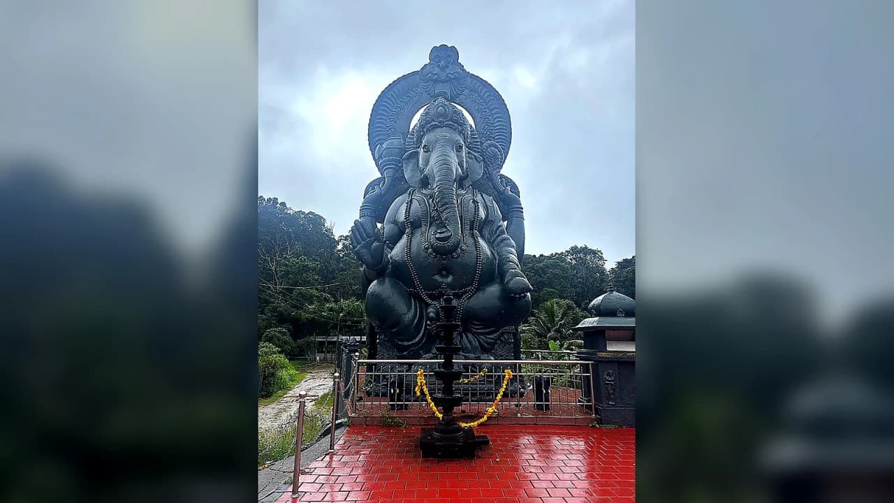 Large black Lord Ganesha statue surrounded by lush greenery along the scenic route from Thekkady to Munnar, Kerala.