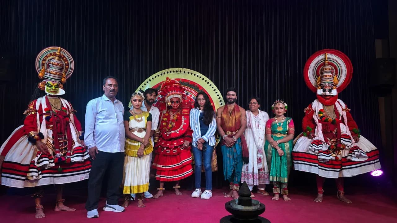 Group photograph on stage with Kathakali performers in elaborate traditional costumes and makeup after a cultural performance in Munnar, Kerala.